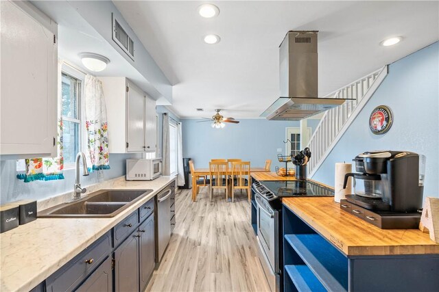 607 E 11th St, Bishop, TX 78343 - kitchen with island exhaust hood, range with electric stovetop, wood counters, white microwave, and a sink