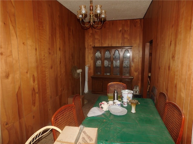 dining room featuring a chandelier and wooden walls