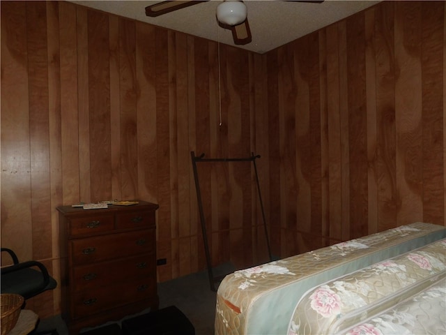 bedroom with wood walls, ceiling fan, and a textured ceiling