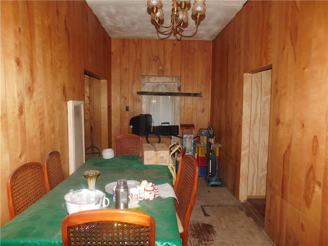 dining room with a chandelier, wooden walls, and a textured ceiling