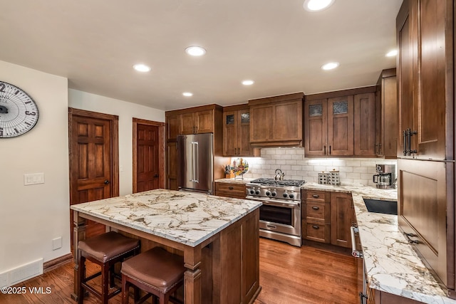 2010 Vermont Rd E, Vail, CO 81657 - kitchen featuring premium appliances, dark wood-style flooring, a breakfast bar area, backsplash, and a center island
