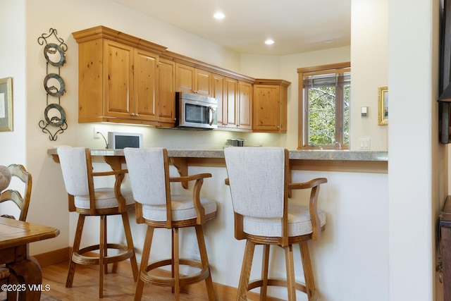 111 Club Cottage Dr, Edwards, CO 81632 - kitchen featuring stainless steel microwave, a breakfast bar, wood finished floors, recessed lighting, and light countertops