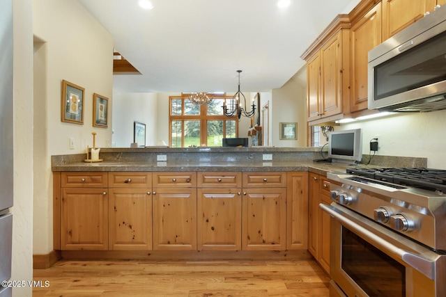 111 Club Cottage Dr, Edwards, CO 81632 - kitchen with appliances with stainless steel finishes, light wood-style floors, a chandelier, decorative light fixtures, and a peninsula