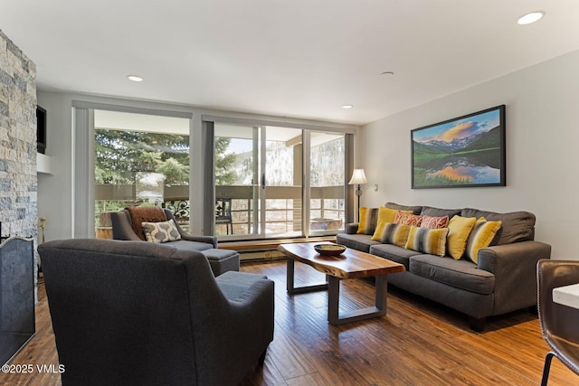 living room with expansive windows, a stone fireplace, wood finished floors, and recessed lighting