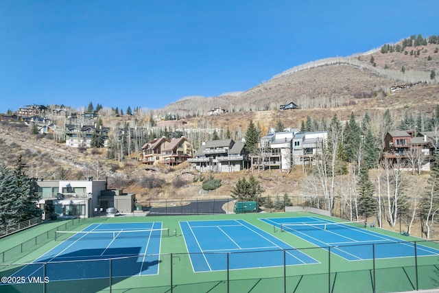 view of sport court featuring a residential view, fence, and a mountain view