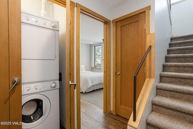 washroom with laundry area, stacked washing maching and dryer, and wood finished floors