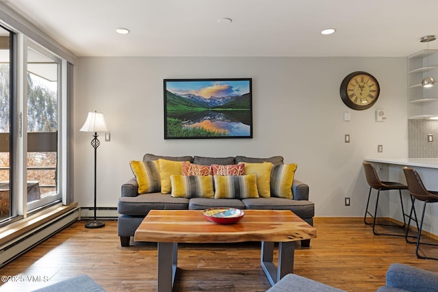 living room featuring light wood finished floors, a baseboard radiator, and recessed lighting