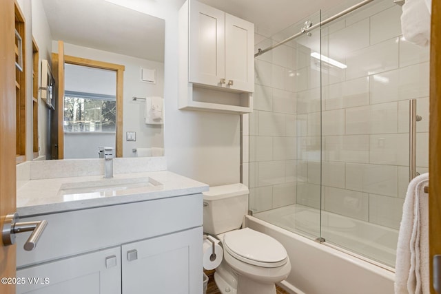 bathroom featuring toilet, bath / shower combo with glass door, and vanity