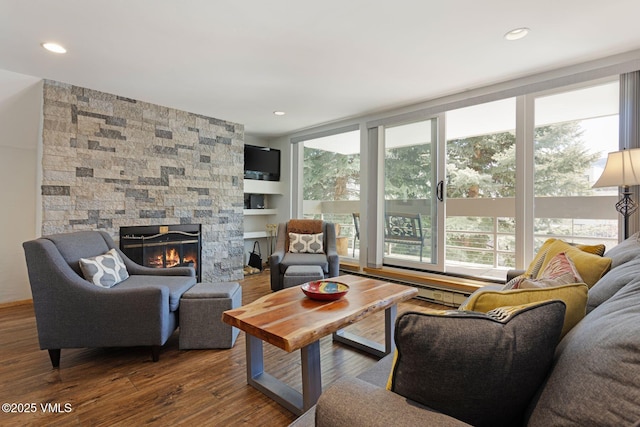 living area with a stone fireplace, recessed lighting, wood finished floors, and a healthy amount of sunlight