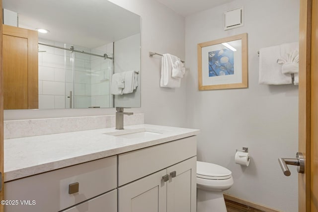 bathroom featuring toilet, wood finished floors, vanity, baseboards, and a stall shower