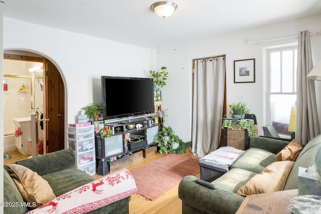 living area featuring arched walkways and wood finished floors