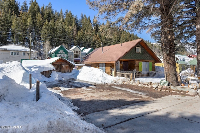 view of front of property with metal roof, covered porch, driveway, and log siding