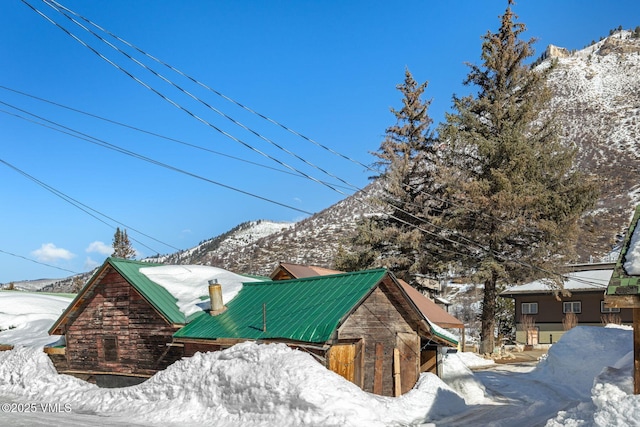 snow covered property featuring a mountain view and metal roof