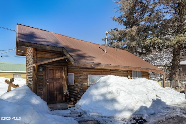 snow covered property featuring metal roof and log siding