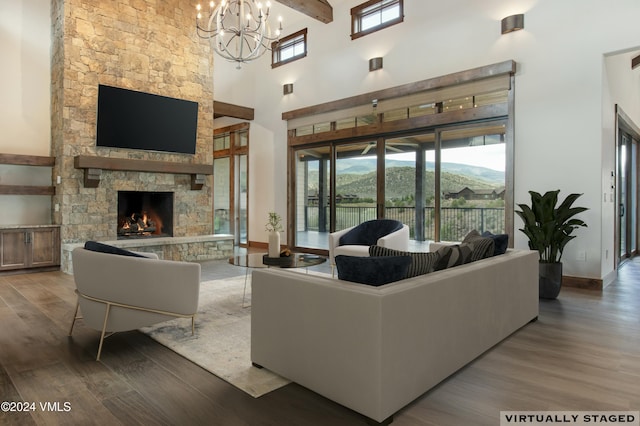 living room featuring hardwood / wood-style flooring, a high ceiling, a notable chandelier, and a fireplace