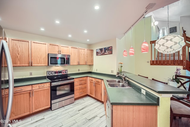 705 Crazy Horse Cir, Edwards, CO 81632 - kitchen featuring stainless steel appliances, a peninsula, a sink, light wood-style flooring, and dark countertops