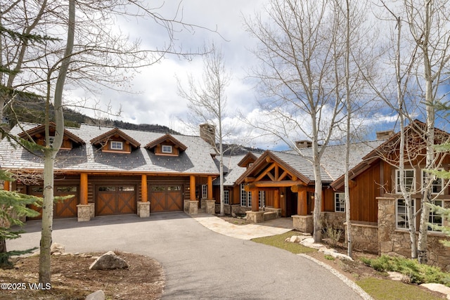 37 Aspen Meadows Rd, Edwards, CO 81632 - view of front facade featuring stone siding, driveway, an attached garage, and a chimney
