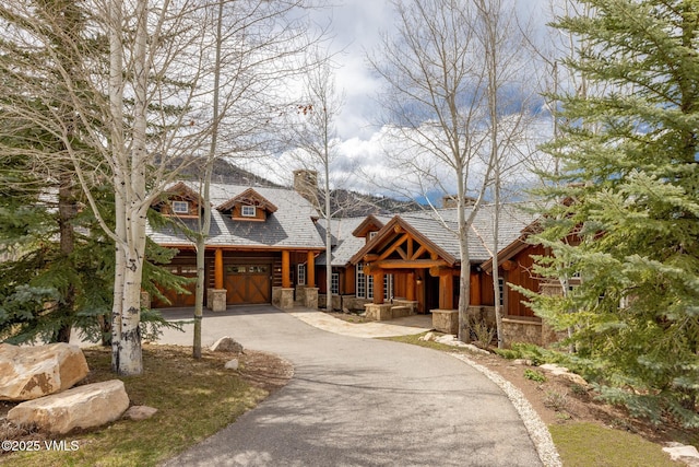 37 Aspen Meadows Rd, Edwards, CO 81632 - view of front facade featuring stone siding, driveway, a chimney, and an attached garage