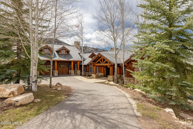 37 Aspen Meadows Rd, Edwards, CO 81632 - view of front of home featuring stone siding, asphalt driveway, a garage, and a chimney