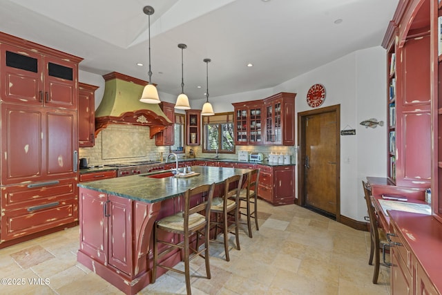 225 Alcazar Dr, Edwards, CO 81632 - kitchen with reddish brown cabinets, custom exhaust hood, dark countertops, backsplash, and hanging light fixtures