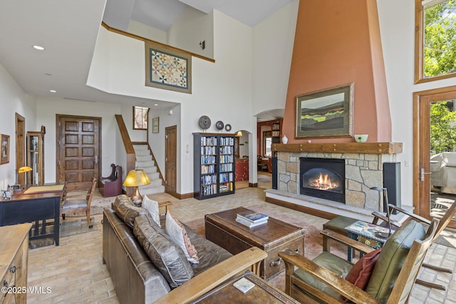 225 Alcazar Dr, Edwards, CO 81632 - living room featuring a stone fireplace, a high ceiling, brick patterned flooring, arched walkways, and stairs