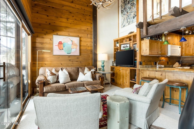 living area with carpet floors, wood walls, and a towering ceiling