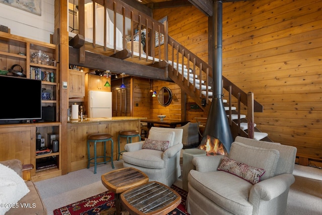 living room featuring wooden walls, stairs, and a towering ceiling