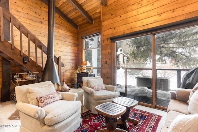 living area with a wood stove, wood ceiling, carpet, and wood walls