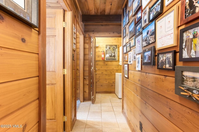 corridor with wooden walls, wood ceiling, and light tile patterned flooring