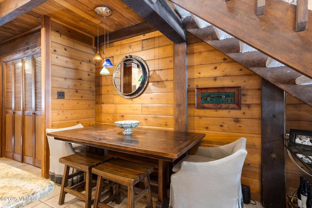 dining room featuring wooden ceiling, wooden walls, and light tile patterned floors