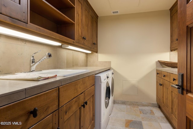 laundry area featuring cabinets, separate washer and dryer, and sink