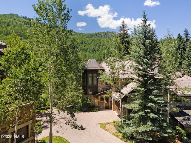 153 Village Walk, Beaver Creek, CO 81620 - view of front facade with a wooded view, a standing seam roof, a metal roof, and decorative driveway