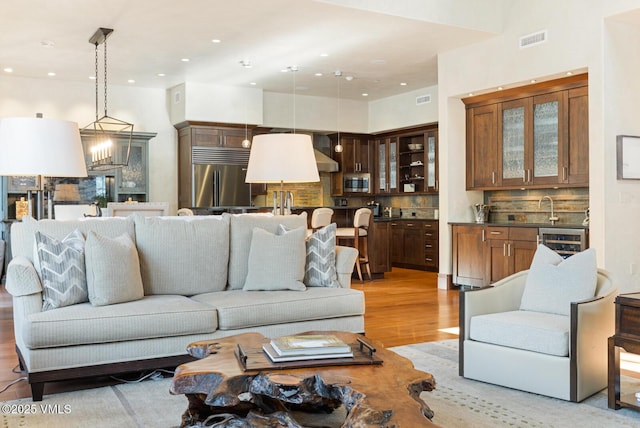 living room featuring wine cooler, sink, and light wood-type flooring