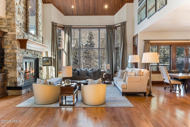 living room featuring a towering ceiling, a fireplace, and light wood-type flooring