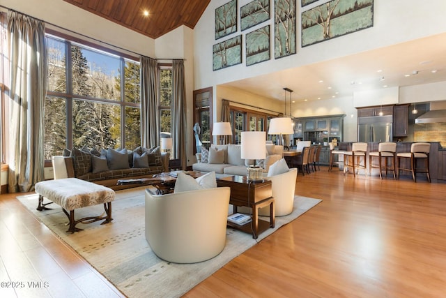 living room with high vaulted ceiling, light hardwood / wood-style floors, and wooden ceiling