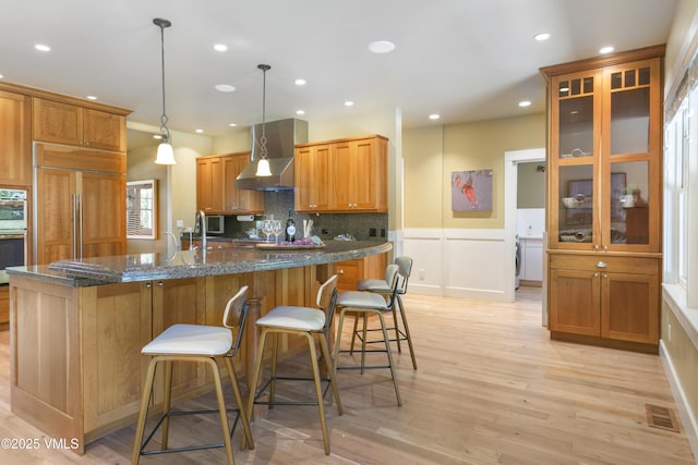 88 E Double Hitch, Eagle, CO 81631 - kitchen featuring wall chimney exhaust hood, light wood finished floors, a breakfast bar, backsplash, and recessed lighting