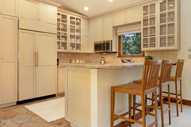 355 Offerson Rd Unit P4, Beaver Creek, CO 81620 - kitchen with stainless steel microwave, tasteful backsplash, a breakfast bar, glass insert cabinets, and recessed lighting