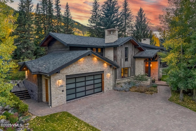 2764 S Frontage Rd, Vail, CO 81657 - modern home with a chimney, stone siding, an attached garage, and decorative driveway