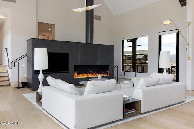 1092 Fourth Of July Rd, Eagle, CO 81631 - living area featuring high vaulted ceiling, wood finished floors, stairs, and a warm lit fireplace