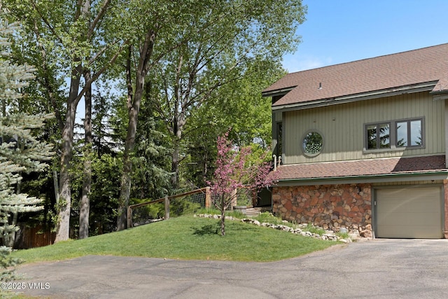 26 Lark Ct Unit B, Eagle-Vail, CO 81620 - view of side of home featuring stone siding, asphalt driveway, a shingled roof, and a garage