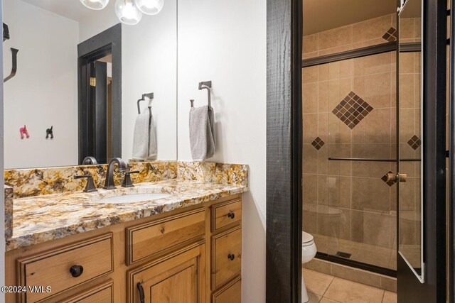 bathroom with tile patterned flooring, vanity, toilet, and an enclosed shower