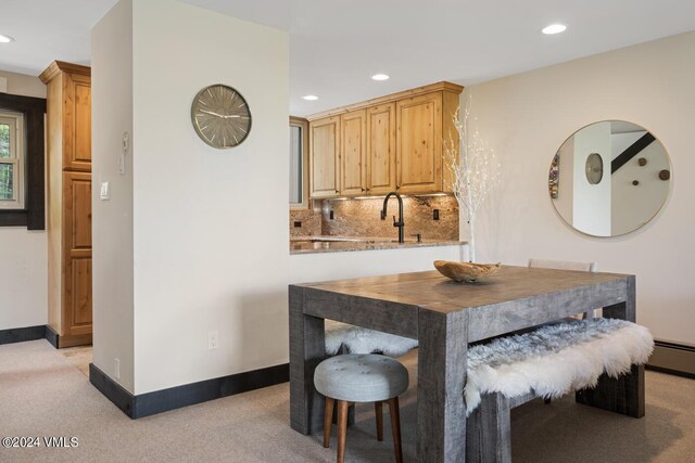 carpeted dining area with a baseboard radiator and sink