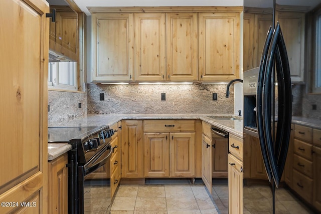 kitchen with sink, light stone counters, and black appliances