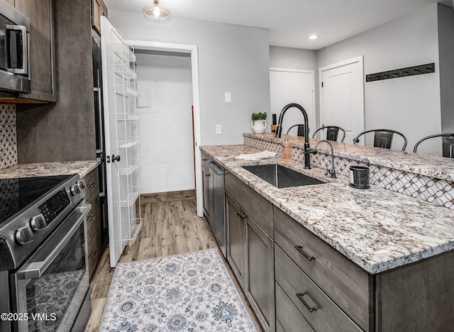 3971 Big Horn Rd Unit 7-N, Vail, CO 81657 - kitchen with appliances with stainless steel finishes, dark brown cabinets, light stone counters, light wood-style flooring, and recessed lighting