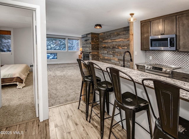 3971 Big Horn Rd Unit 7-N, Vail, CO 81657 - kitchen with stainless steel appliances, dark brown cabinetry, open floor plan, light stone counters, and a breakfast bar area
