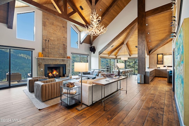 living room featuring an inviting chandelier, hardwood / wood-style flooring, a stone fireplace, and wooden ceiling