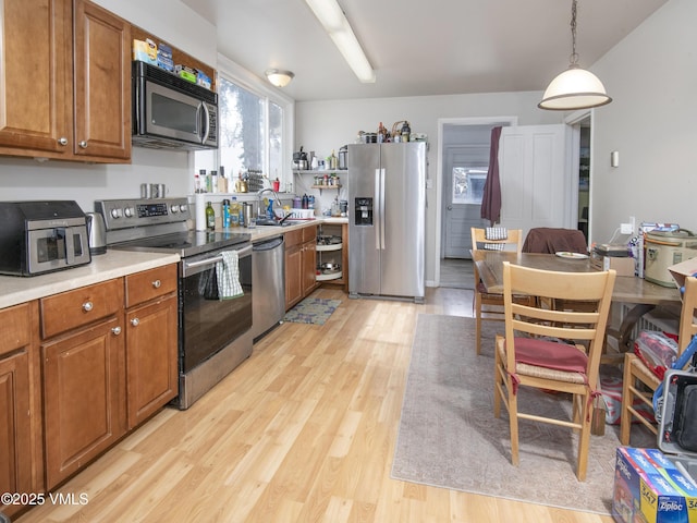 425 Broadway St, Eagle, CO 81631 - kitchen featuring light countertops, light wood-style floors, appliances with stainless steel finishes, pendant lighting, and brown cabinets