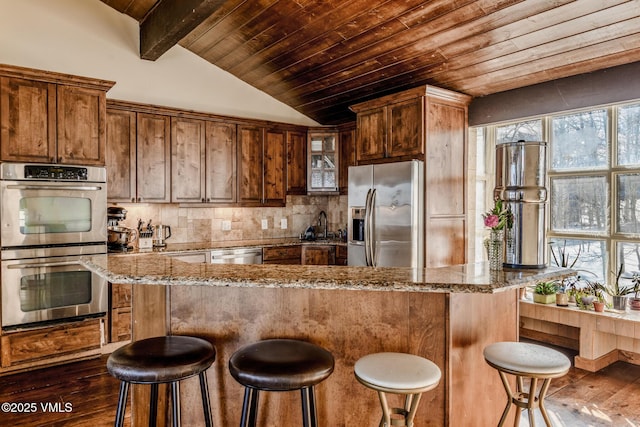 kitchen with dark wood-style floors, stainless steel appliances, tasteful backsplash, lofted ceiling with beams, and wooden ceiling