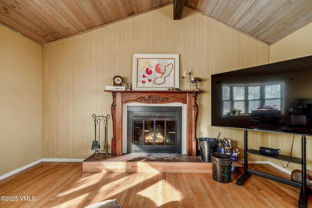 living area featuring a glass covered fireplace, wood ceiling, vaulted ceiling, wood finished floors, and baseboards