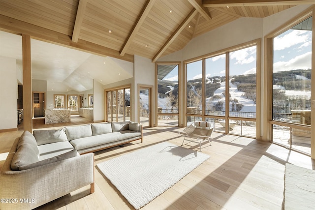 sunken living room with high vaulted ceiling, a mountain view, wood ceiling, light wood-style floors, and beam ceiling